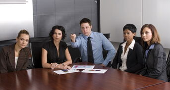 Mehrere Personen sitzen an einem Tisch zur Prüfung