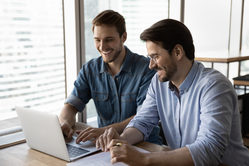 Zwei Teamkollegen arbeiten an einem Laptop
