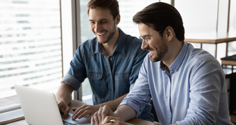 Zwei Teamkollegen arbeiten an einem Laptop