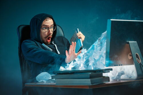 Mann wird vor dem PC von E-Mails überflutet