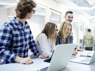 Junges Team schaut auf einen Laptop